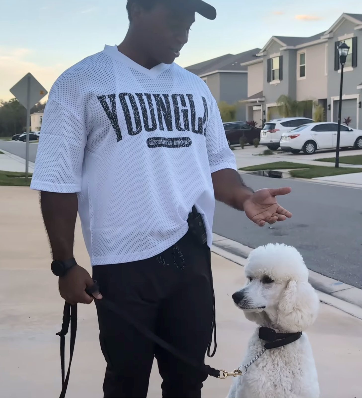 Handler with Romulus, a white Standard Poodle, sitting calmly on leash in a Wesley Chapel-area townhouse community